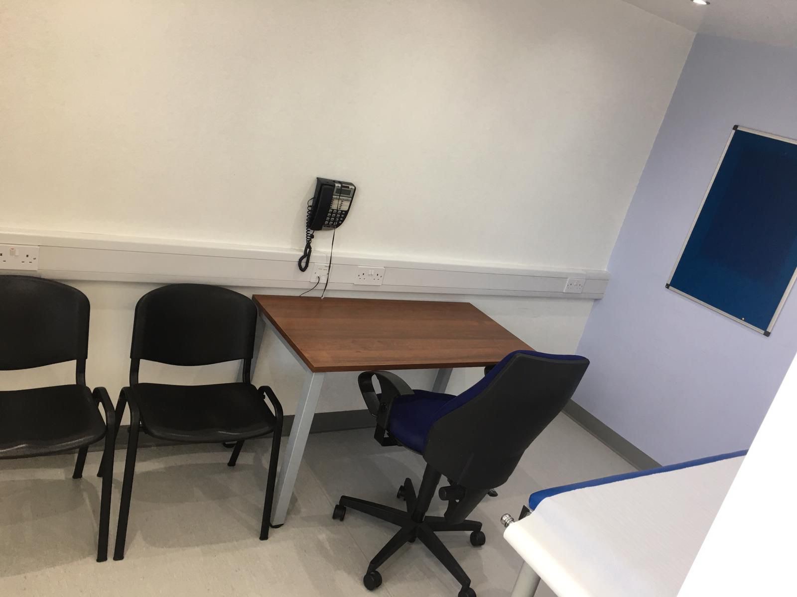 Consulting Room 2 with desk, seating and notice board